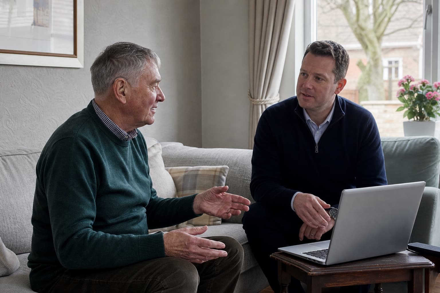 Older man discussing his newly fitted hearing aids with an audiologist during a home appointment