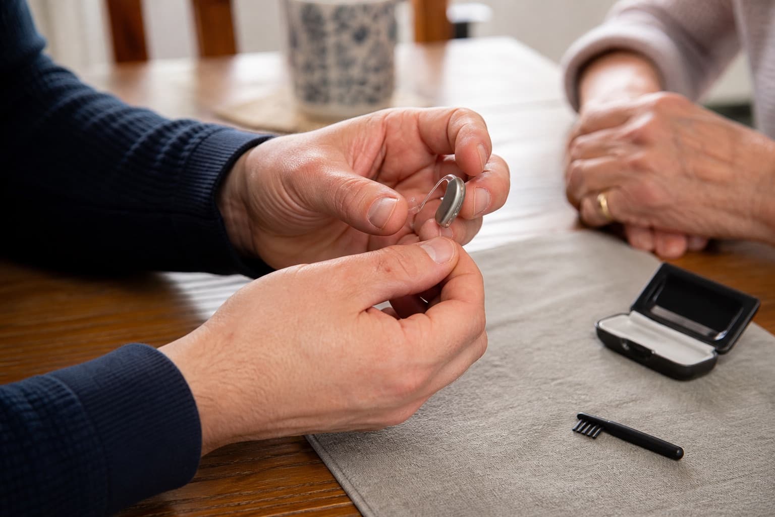 Audiologist inspecting the casing and receiver wire of an existing hearing aid during a home visit