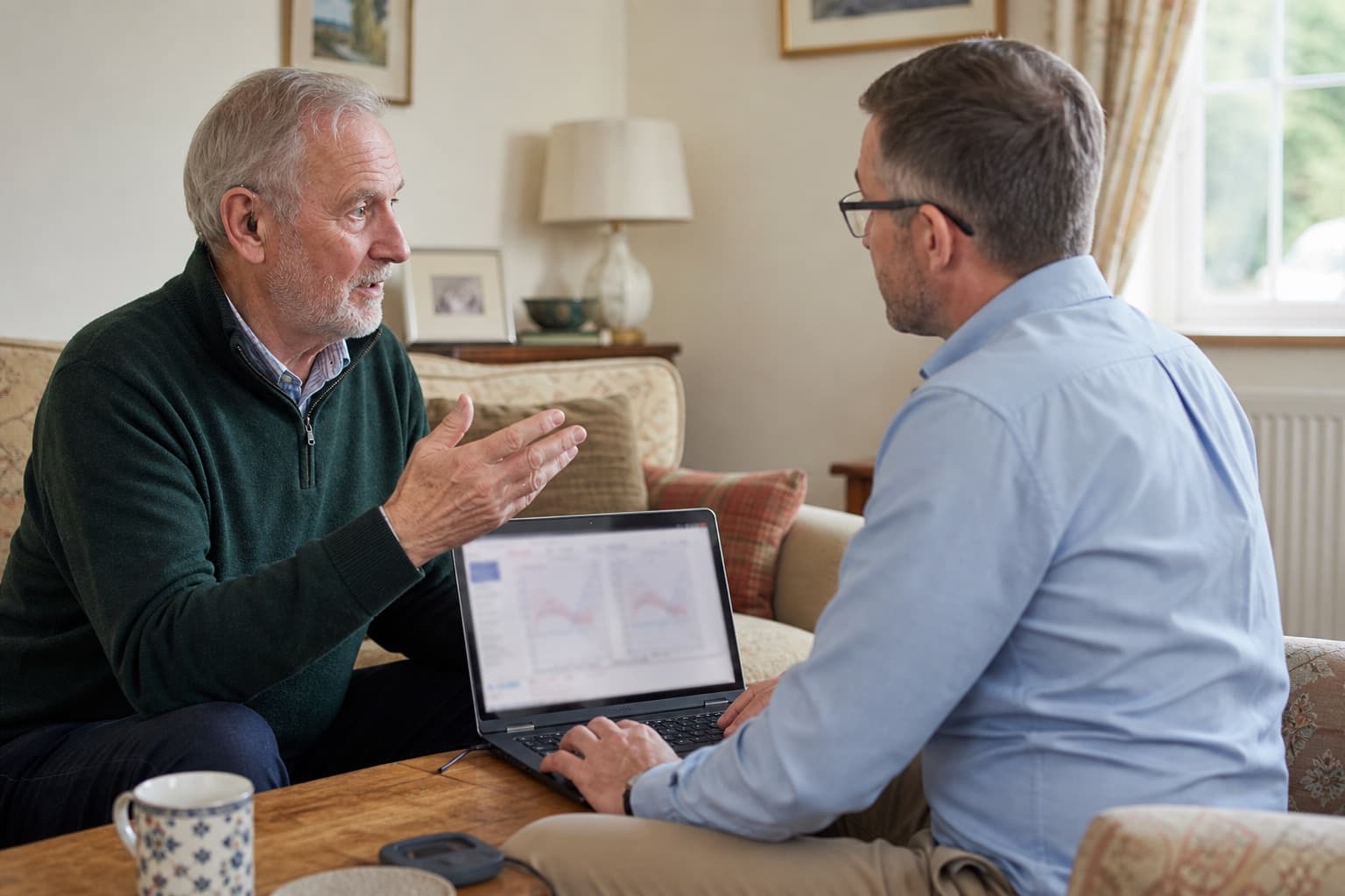 Older hearing-aid wearer discussing his listening experience while an audiologist reviews settings at home