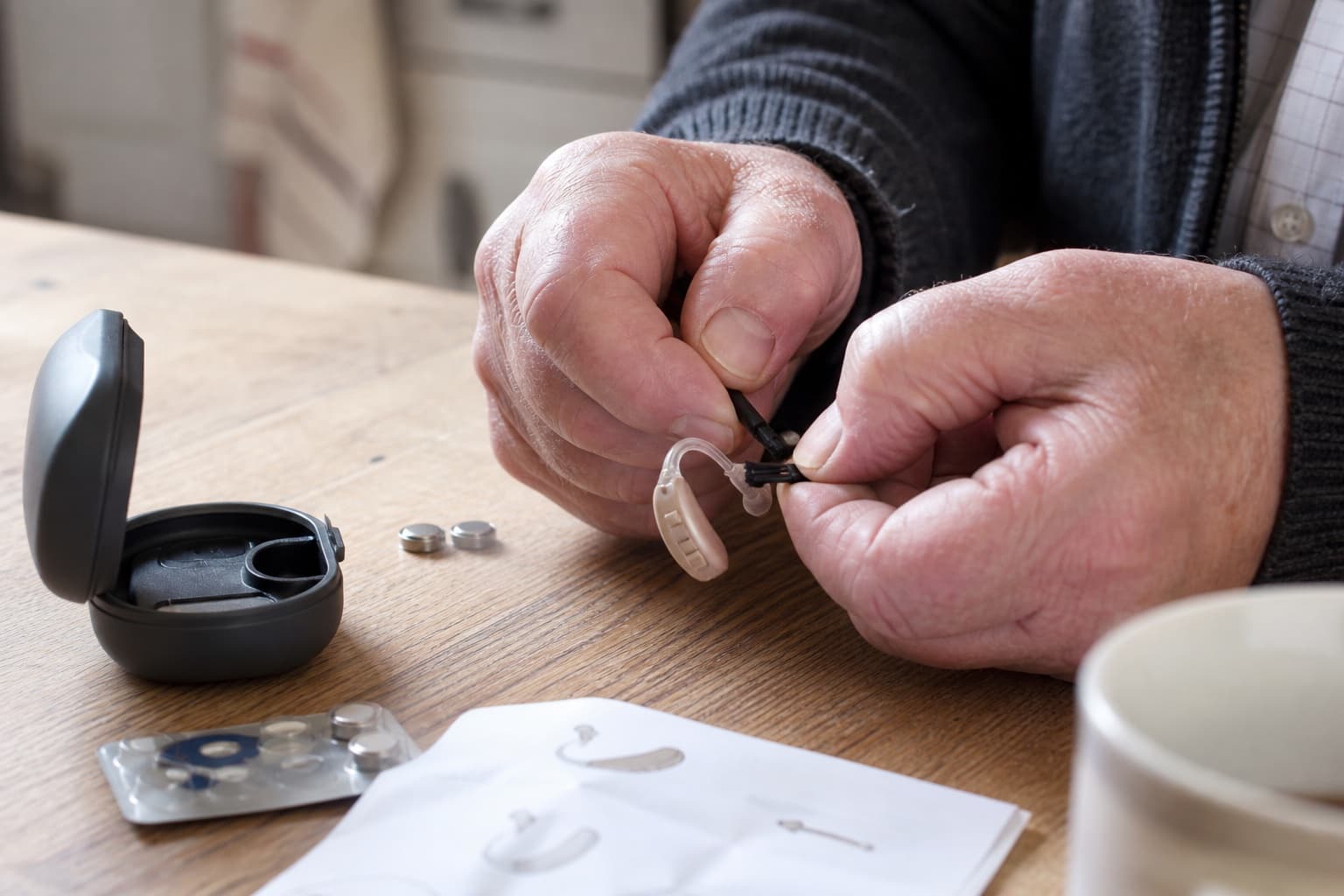 Older hearing-aid wearer cleaning a behind-the-ear device at home