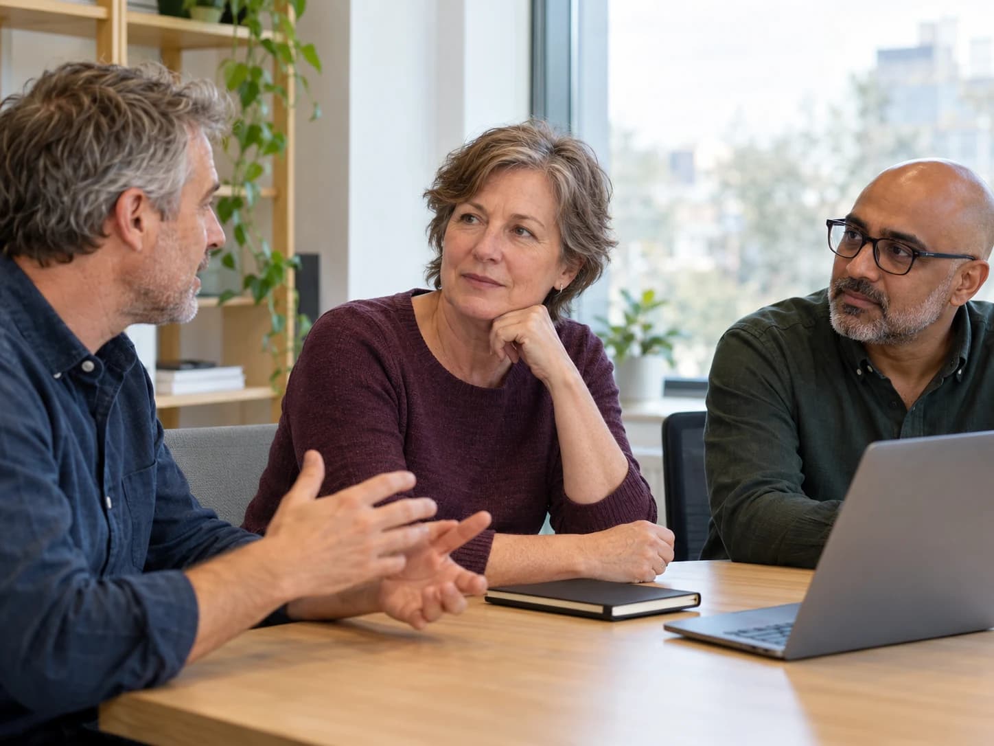 Three colleagues facing one another during a small meeting in a bright modern office